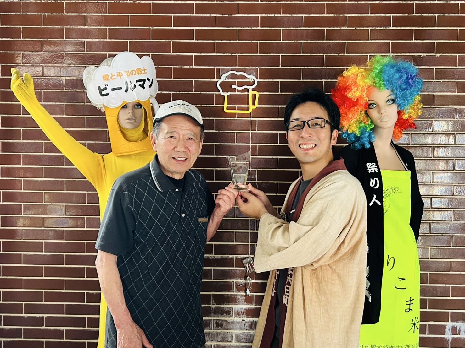 クラウドファンディングアワード大賞のトロフィーを手にする三浦と旧店主